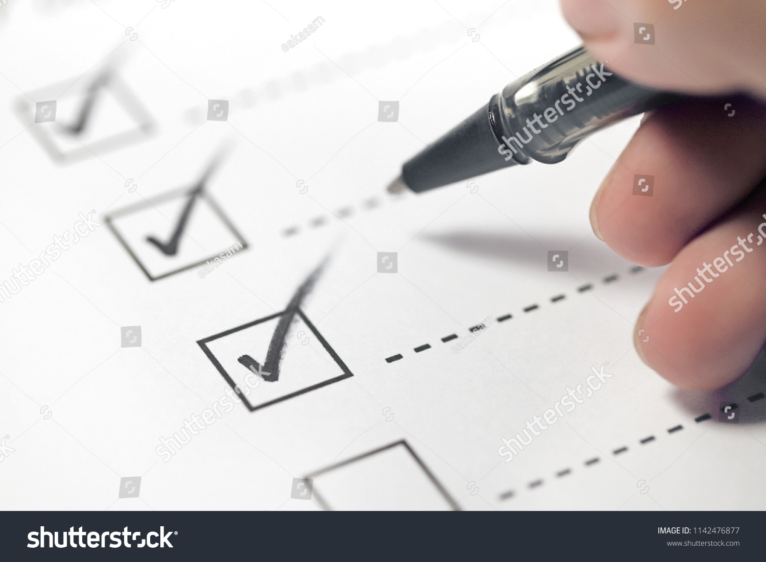 Hand with black pen marking on checklist box. #1142476877