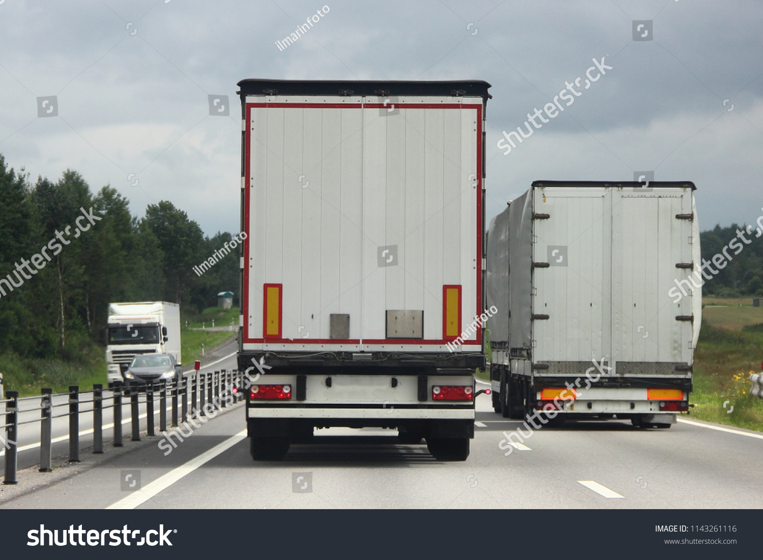Logistics, international freight by road-two white trucks drive next to the two-lane asphalted country road in the summer day, rear view #1143261116