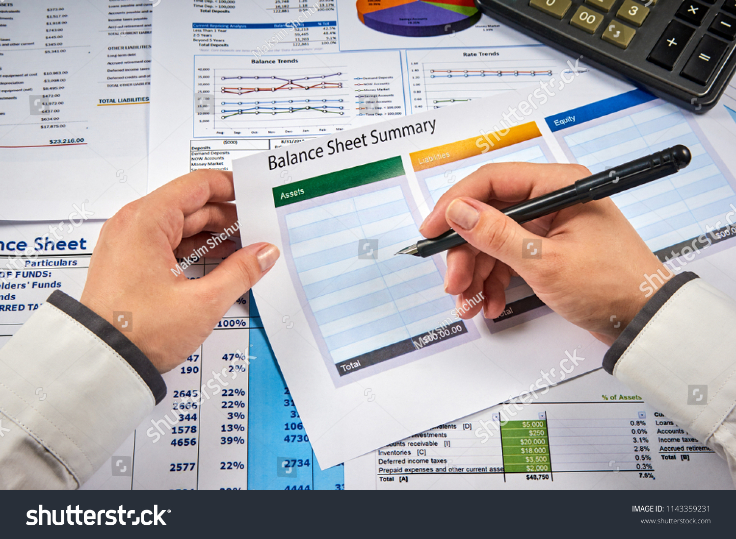 human hands write balance sheet summary on a background balances sheets with calculator #1143359231