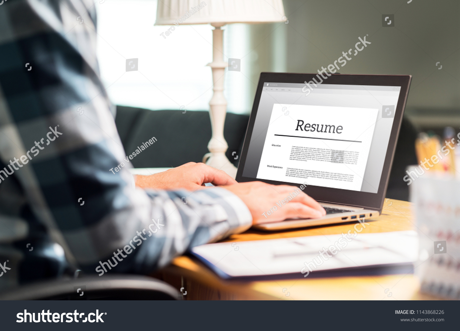 Man writing resume and CV in home office with laptop. Applicant searching for new work and typing curriculum vitae for application. Job seeking, hunt and unemployment. Mock up text in computer screen. #1143868226