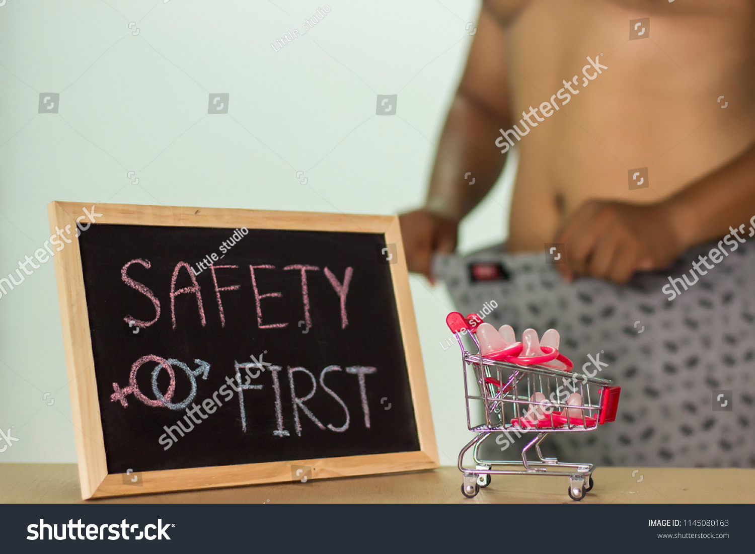 safety first, The blackboard sign reads safety first condom with trolley, male genital concept of an advertisement can be used, About sexuality and the prevention of sexually transmitted diseases. #1145080163