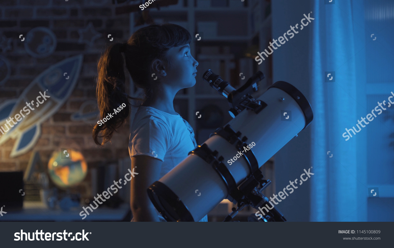 Cute young girl stargazing at night with a telescope, she is looking away: imagination and childhood concept #1145100809