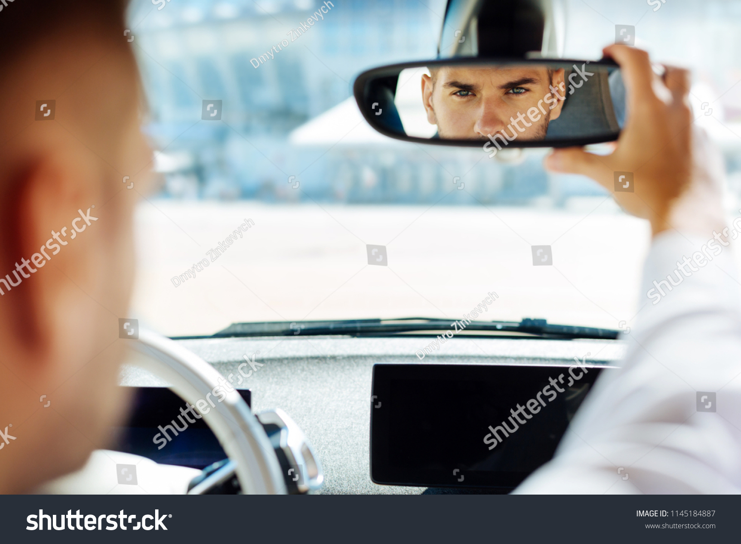 Professional driving. Confident smart man looking into the rearview mirror while driving his car #1145184887