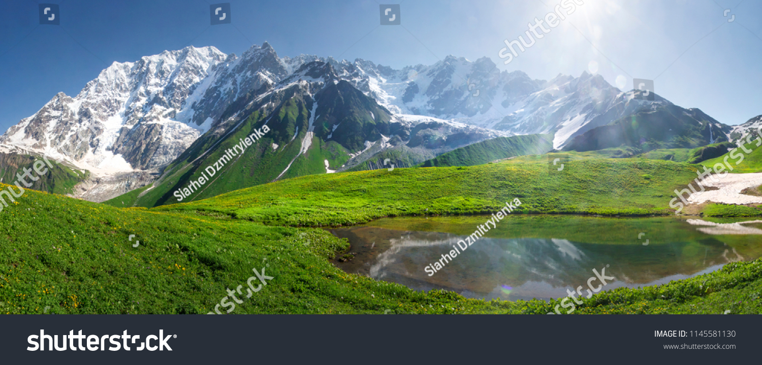 Mountain landscape of Svaneti on bright summer sunny day. Mountain lake, hills covered green grass on snowy rocky mountains background. Caucasus peaks in Georgia. Amazing view on wild georgian nature #1145581130