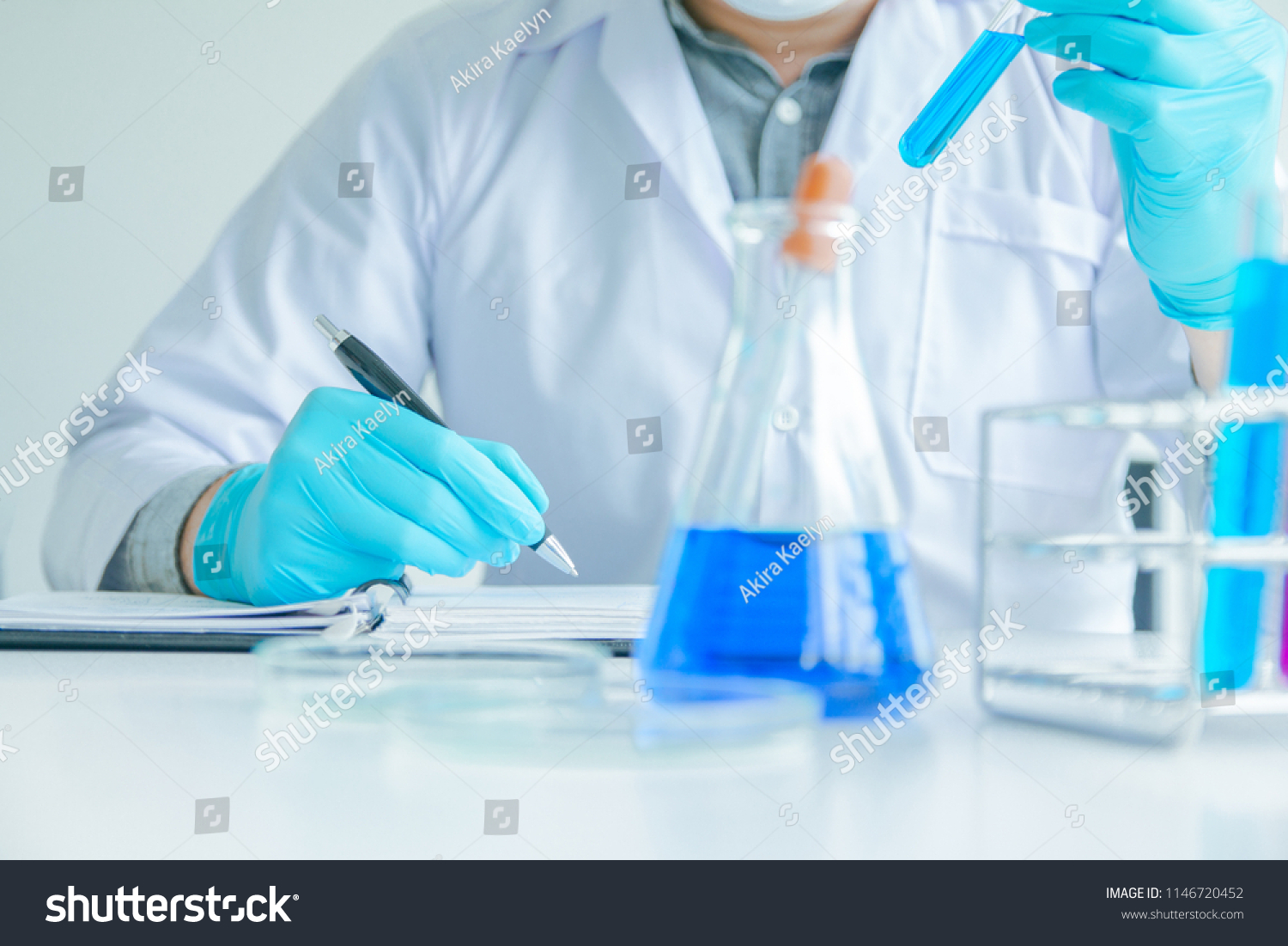 Medical science or male Compiling an Analysis Report in laboratory room research performs tests with blue liquid on test tube, Experimental Drug Treatment Chemicals #1146720452