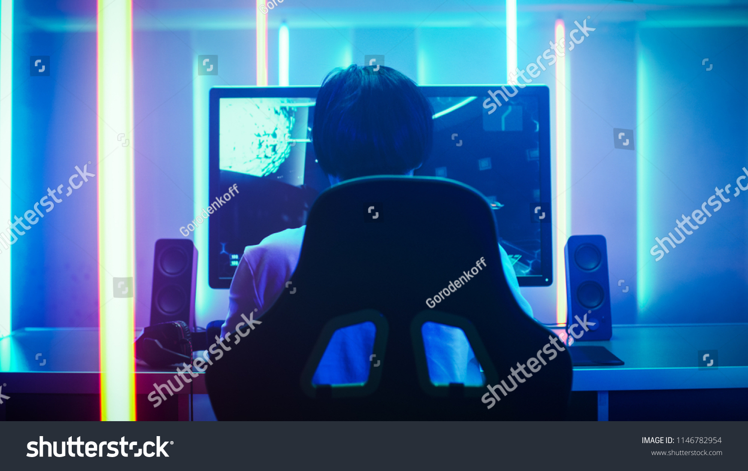 Back View Shot of the Professional Gamer Playing in First-Person Shooter Online Video Game on His Personal Computer. Room Lit by Neon Lights in Retro Arcade Style. Online Cyber e-Sport Internet. #1146782954