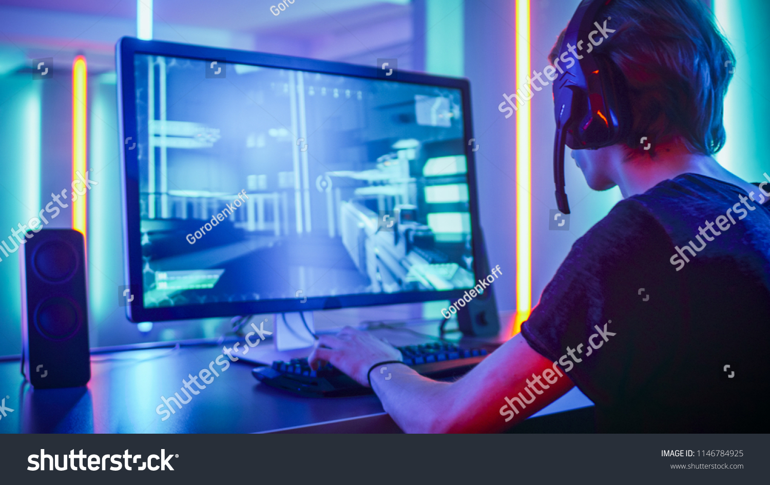 Shot of the Professional Gamer Playing in First-Person Shooter Online Video Game on His Personal Computer. Room Lit by Neon Lights in Retro Arcade Style. Online Cyber e-Sport Internet Championship. #1146784925