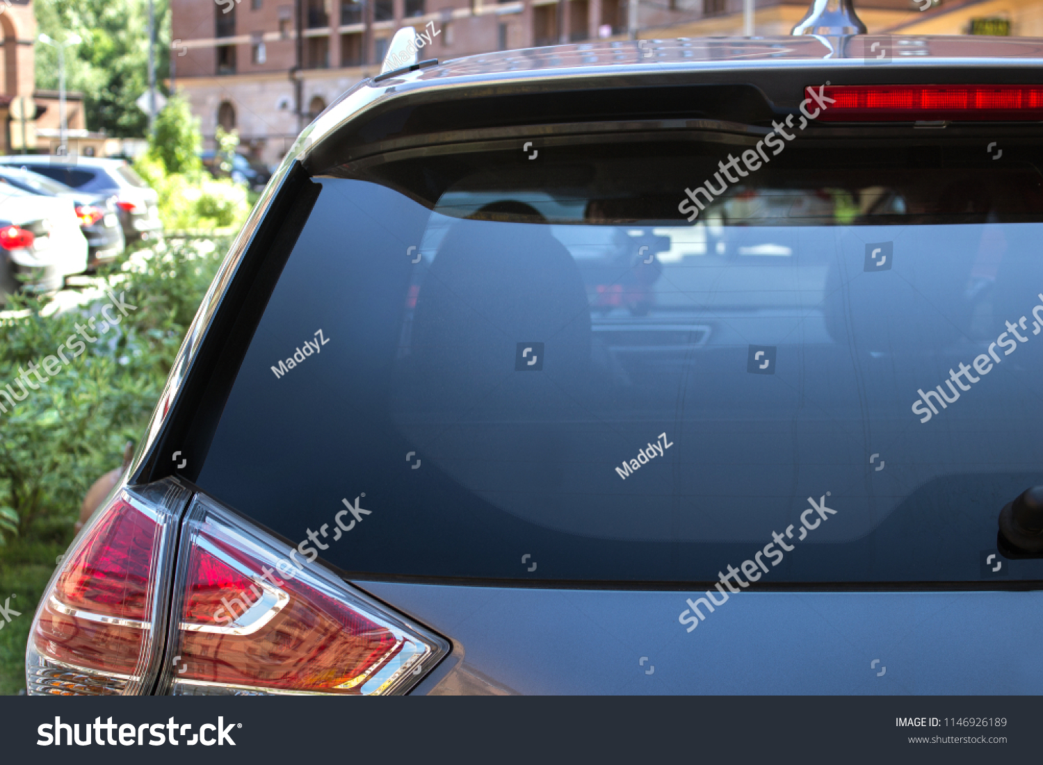 Back window of a car parked on the street in summer sunny day, rear view. Mock-up for sticker or decals #1146926189