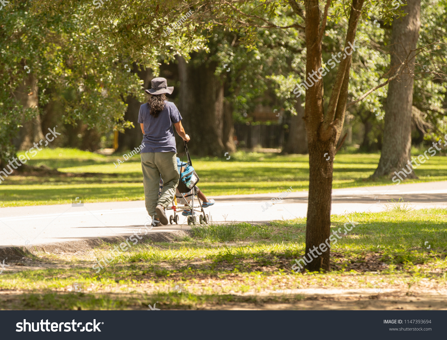 unknown woman with stroller takes her son for a picnic in the park #1147393694