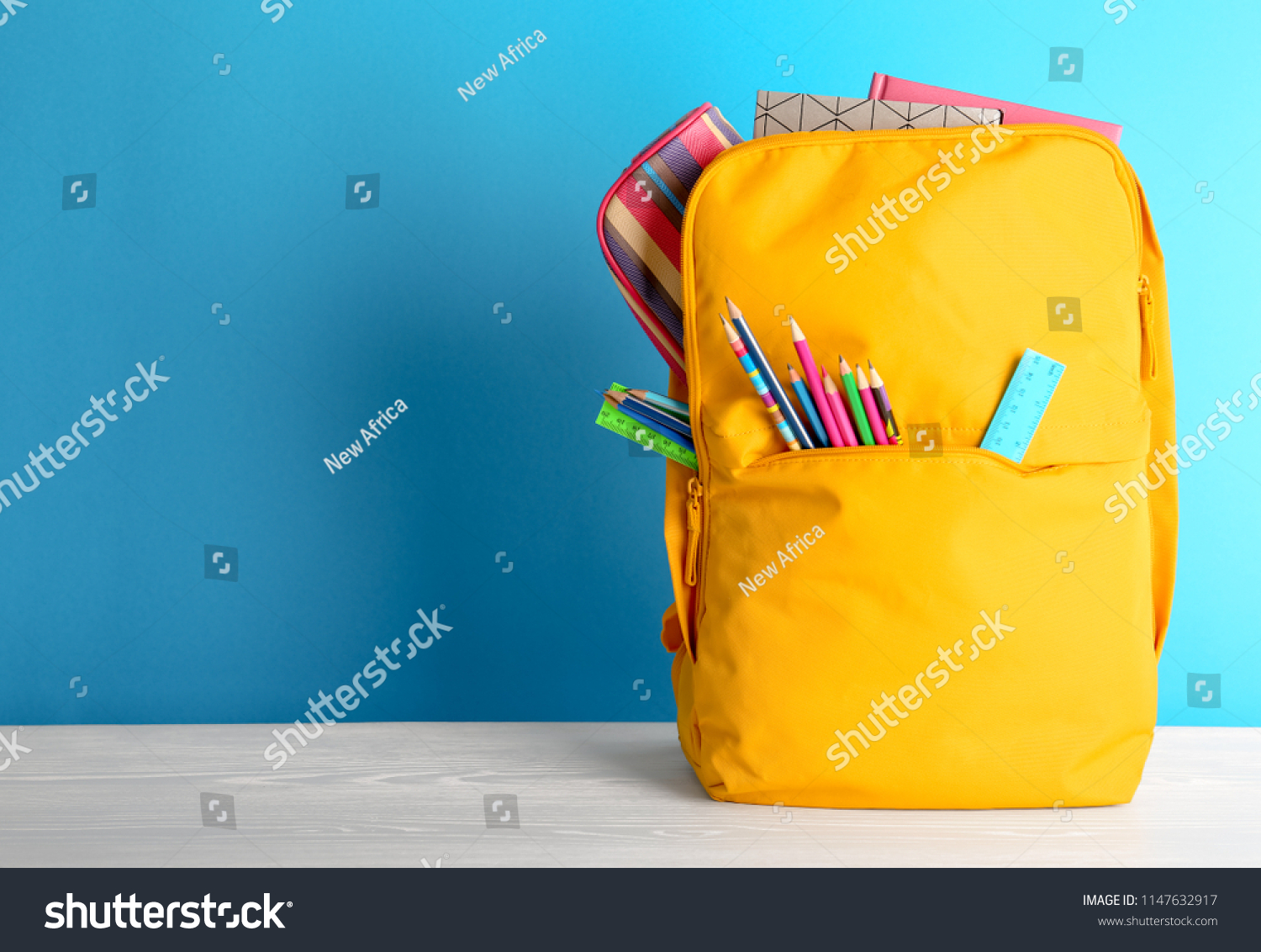 Backpack with different colorful stationery on table. Back to school #1147632917