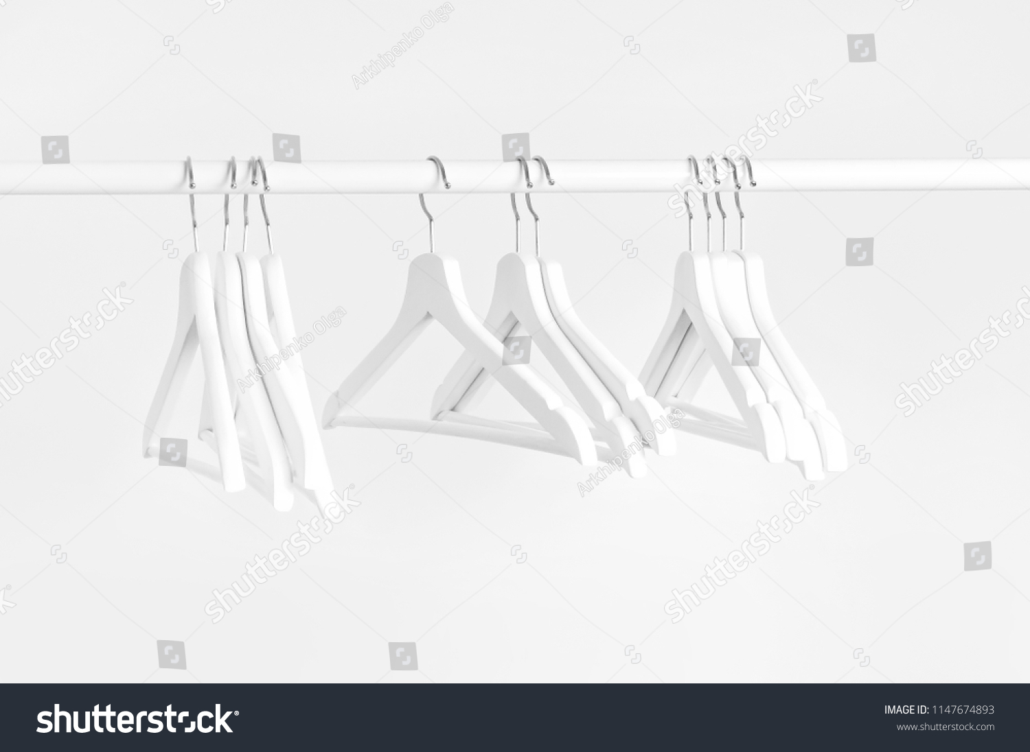 Many wooden white hangers on a rod, isolated on white wall background. Store concept, sale, design, empty hanger. Place for text.  #1147674893