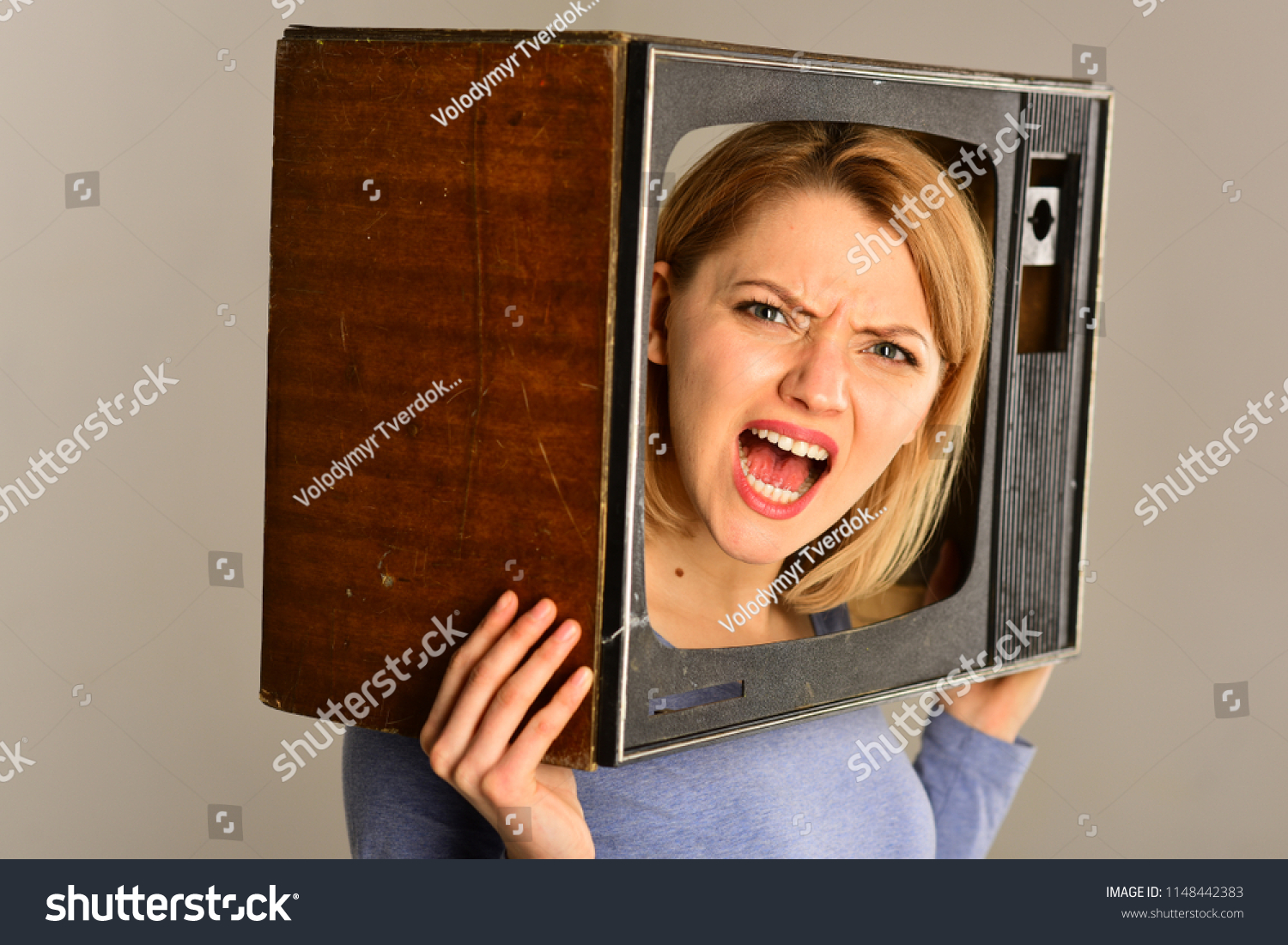 television set. television set on head of angry woman. woman hold television set in hands. television set and new technology. bang #1148442383