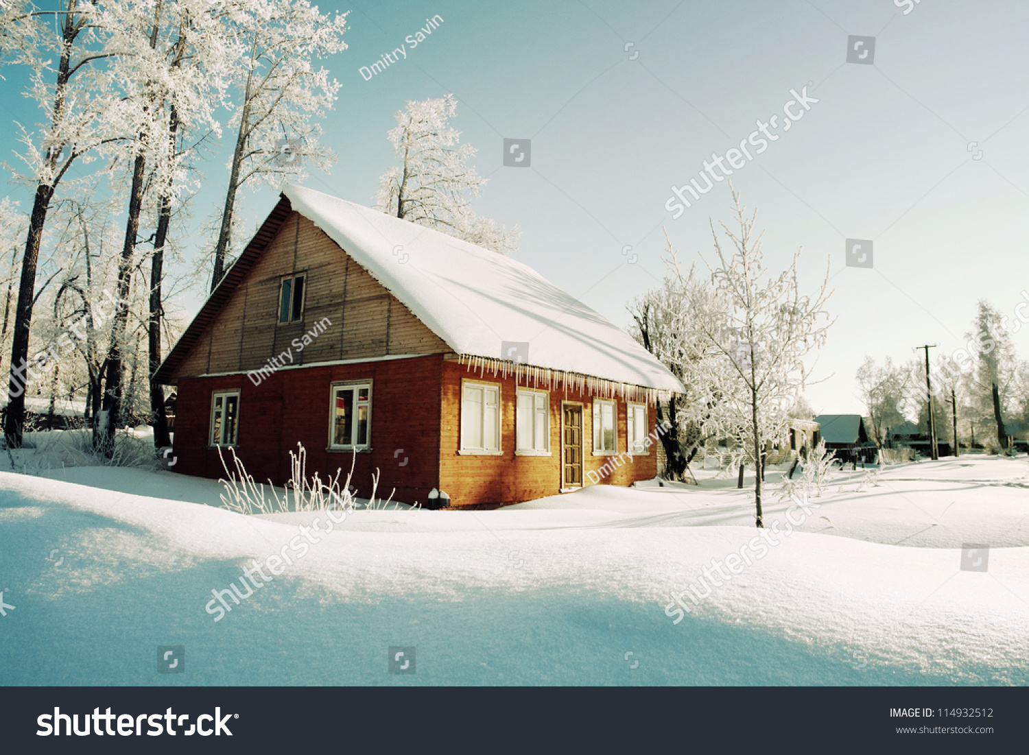 Snowy hills in Russian countryside in morning, red wooden house windows turned to east #114932512