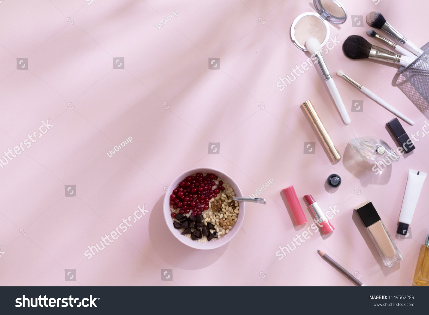Top view of elegant woman make up table with pink and white accents and shadows on background, female morning with healthy breakfast oat flakes with berries, flat lay and copy space #1149562289