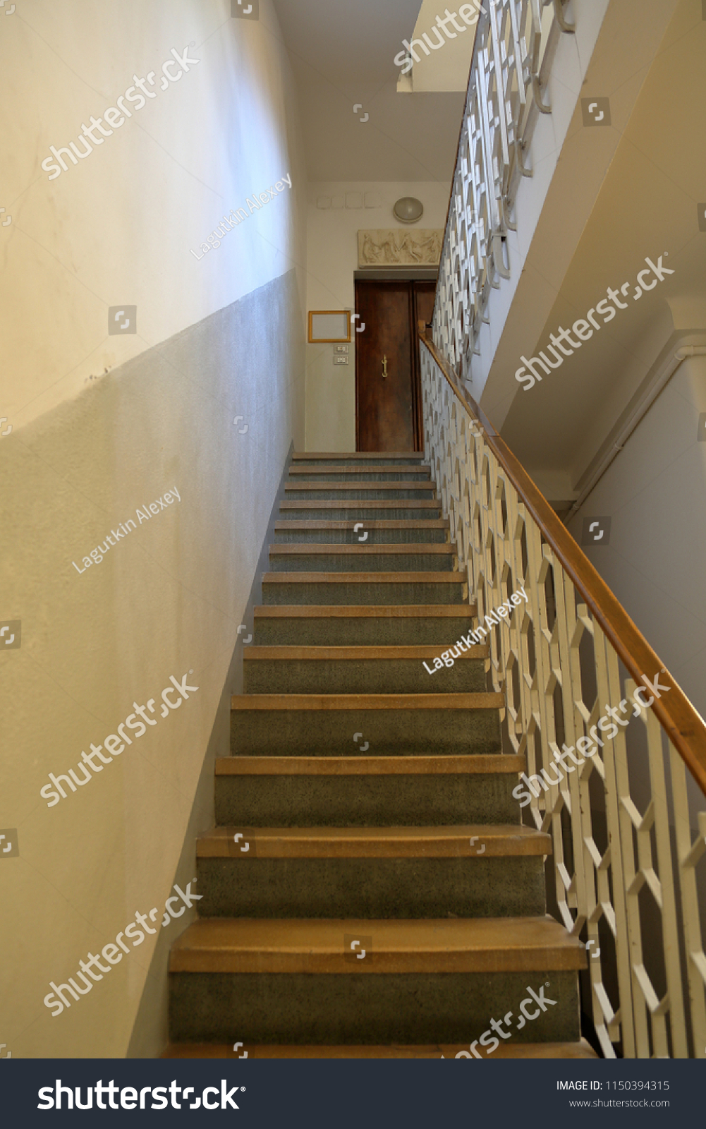 Old stone staircase with a handrail in a building without an elevator #1150394315