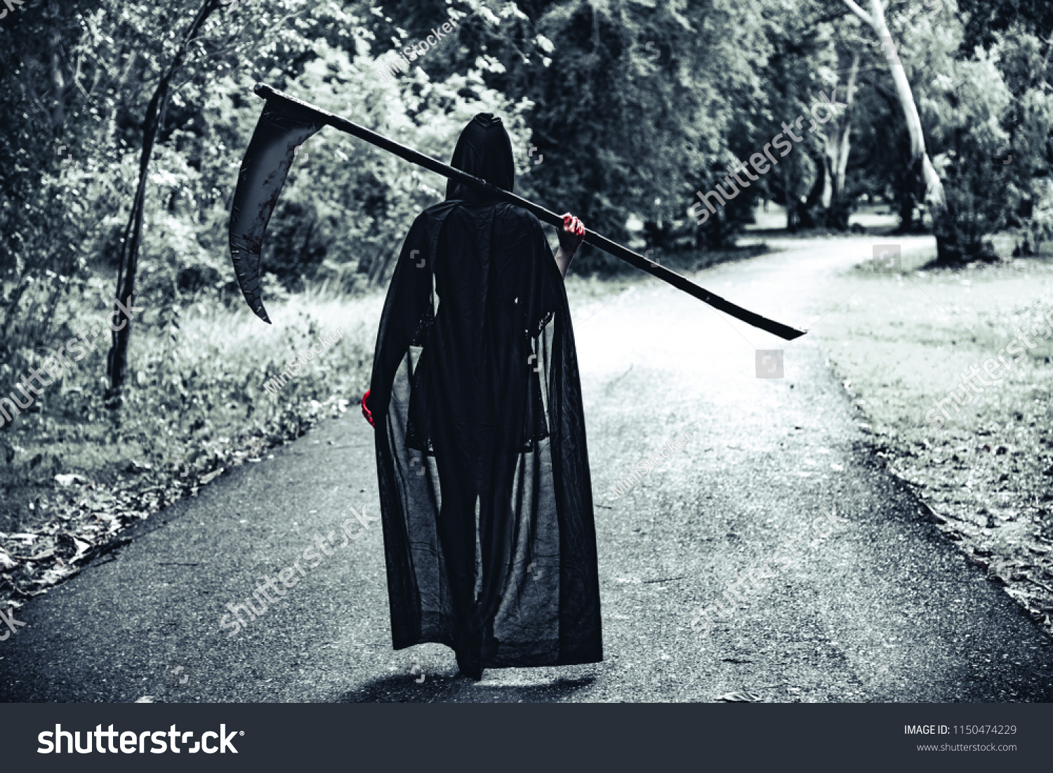 Back view of demon witch with reaper and red blood on hands walking along moon light road background. Horror and Ghost concept. Halloween day and Scary scene theme. Killer and moonlight death theme. #1150474229