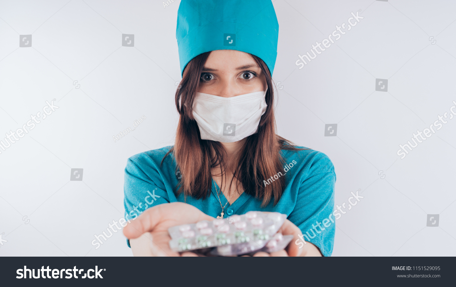 beautiful young doctor woman, with a bandage on his face, isolated on white background. Female doctor in medical gown holds pills. Healthcare personnel, medicine concept #1151529095