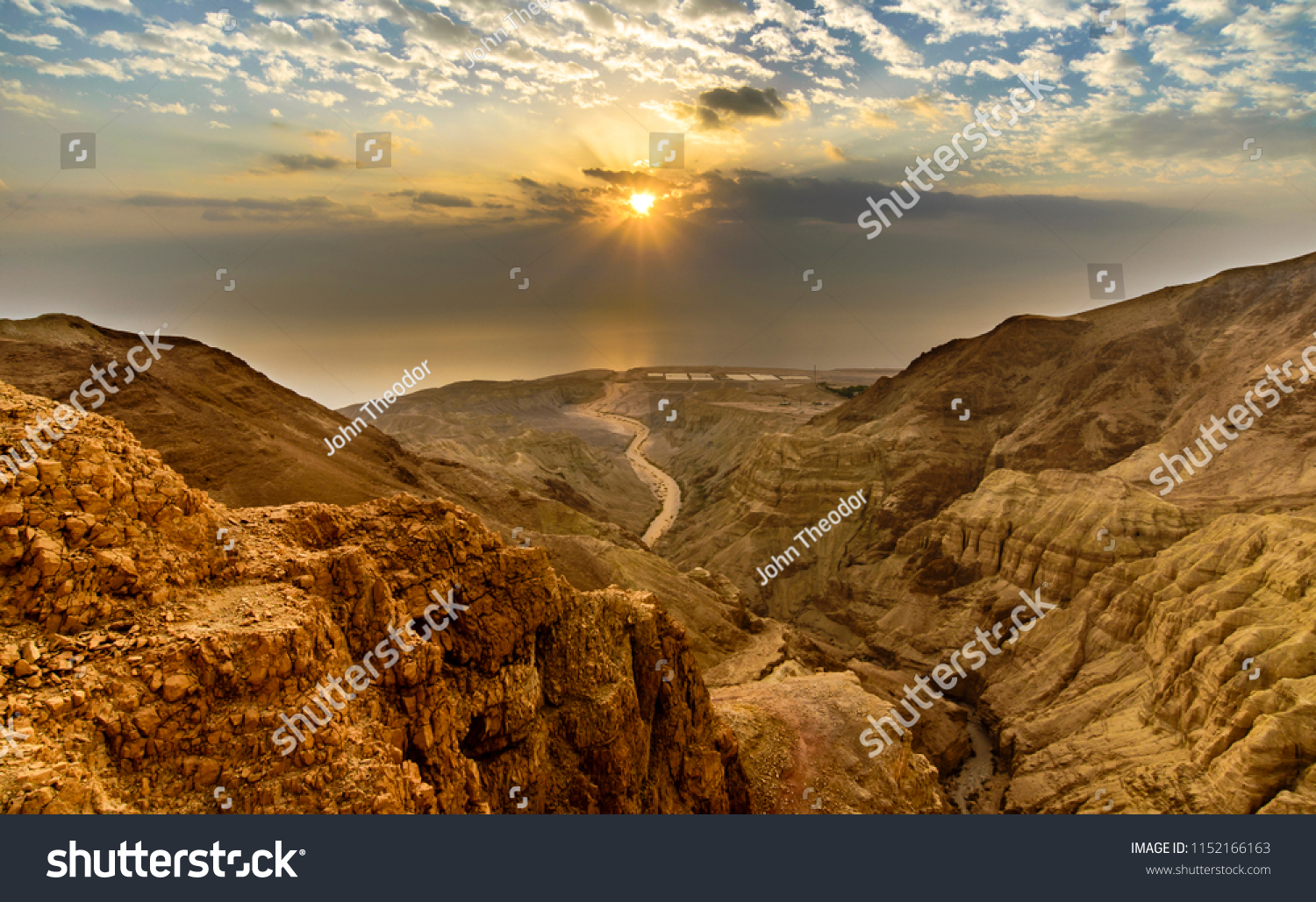 Beautiful landscape of Israeli Judean Desert mountains, with sunrise over the dry riverbed of Nahal Dragot Wadi, popular hiking trail winding between rugged rocky cliffs towards the Dead Sea #1152166163