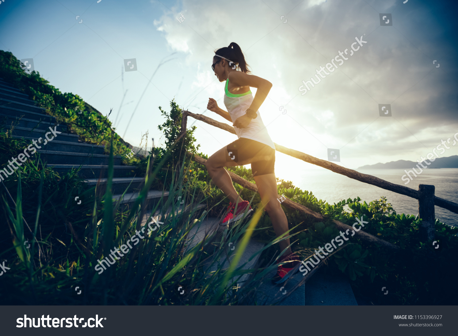 Determined woman running up on seaside mountain stairs #1153396927