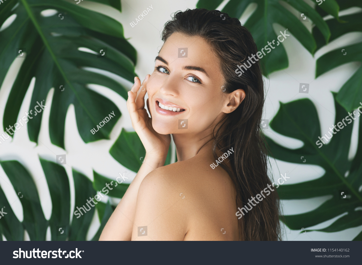 Portrait of young and beautiful woman with perfect smooth skin in tropical leaves. Concept of natural cosmetics and skincare. #1154140162