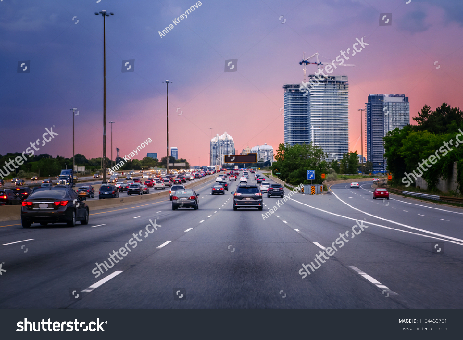 Night traffic. Cars on highway road at sunset evening in typical busy american city. Beautiful amazing night urban view with red, yellow and blue sky clouds. Sundown in downtown. #1154430751
