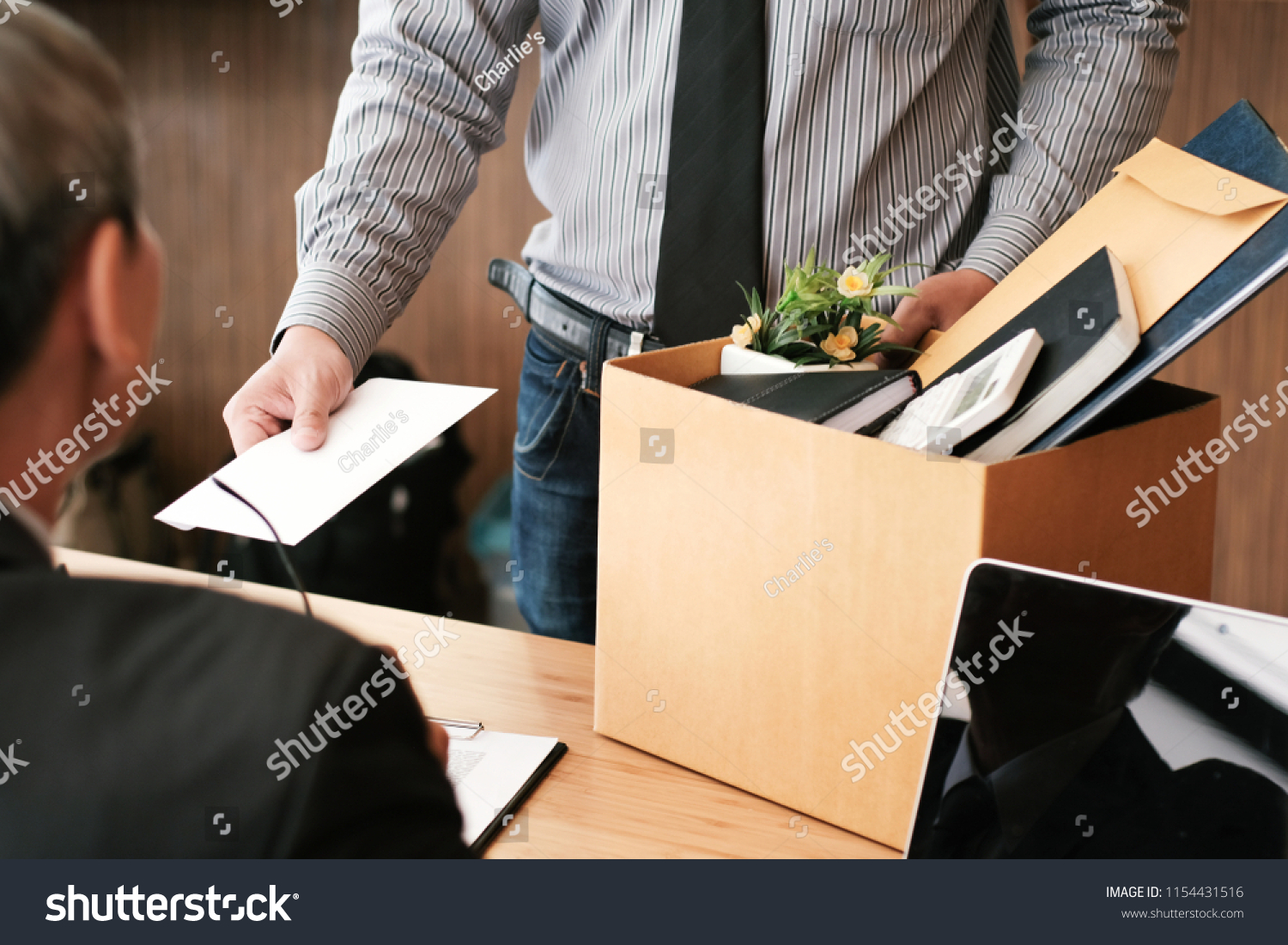 Business man sending resignation letter to boss and Holding Stuff Resign Depress or carrying cardboard box by desk in office #1154431516