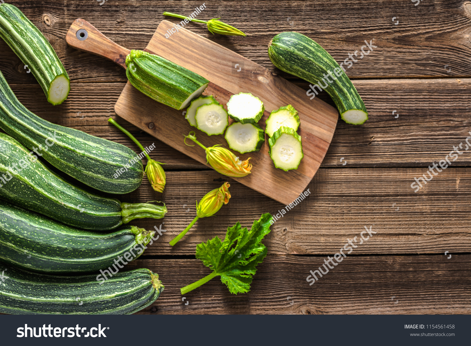 Fresh zucchini and slices of zucchinis on wooden table. Sliced courgette, healthy vegan diet or vegetarian food, cooking concept. #1154561458