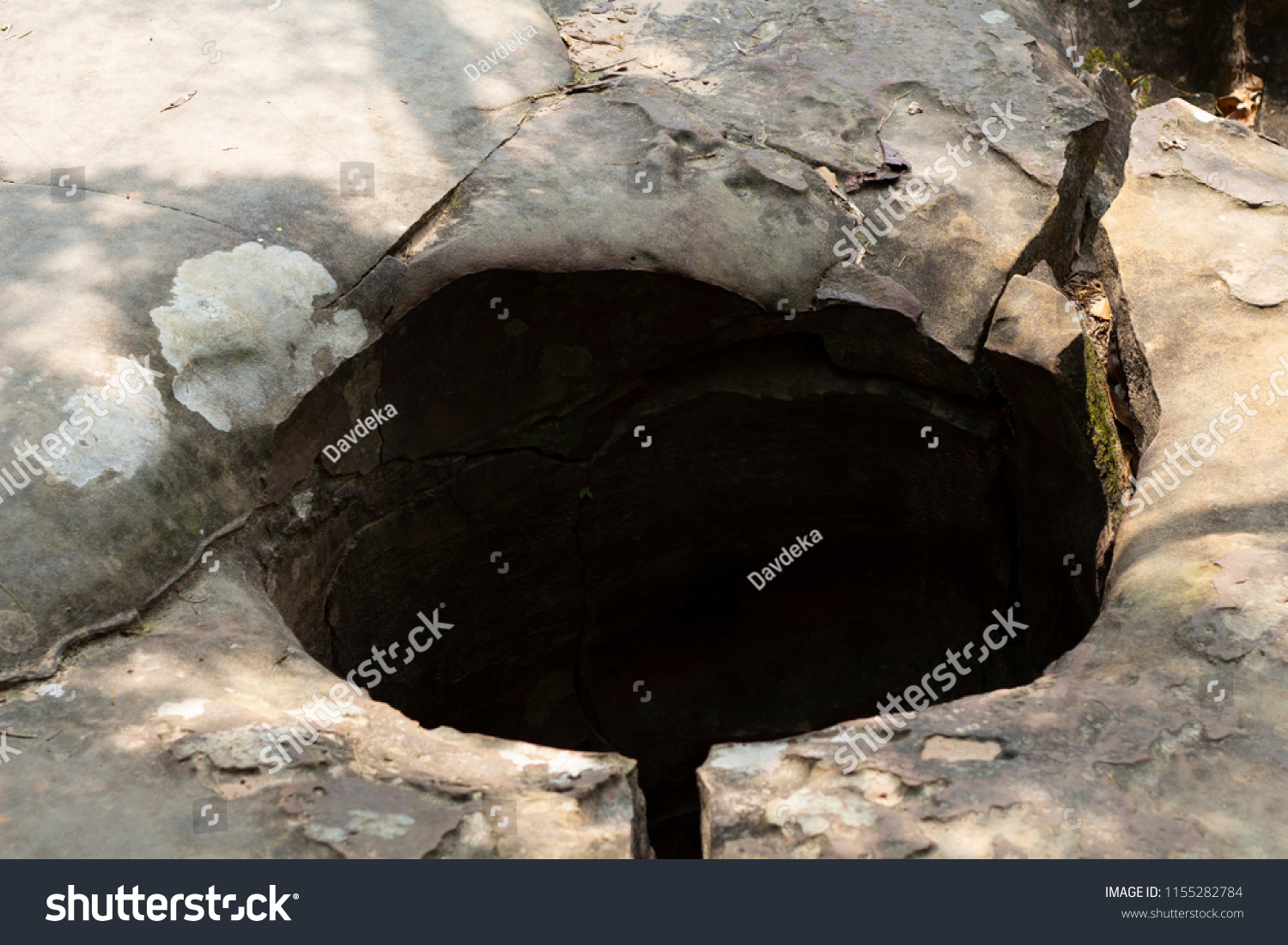 Water hole in solid rock, natural landscape formation. Geological formation of stone mountain. Water flow channel. Cracked rock. Geographical feature of rock in tropical jungle. Kbal Spean in Cambodia #1155282784