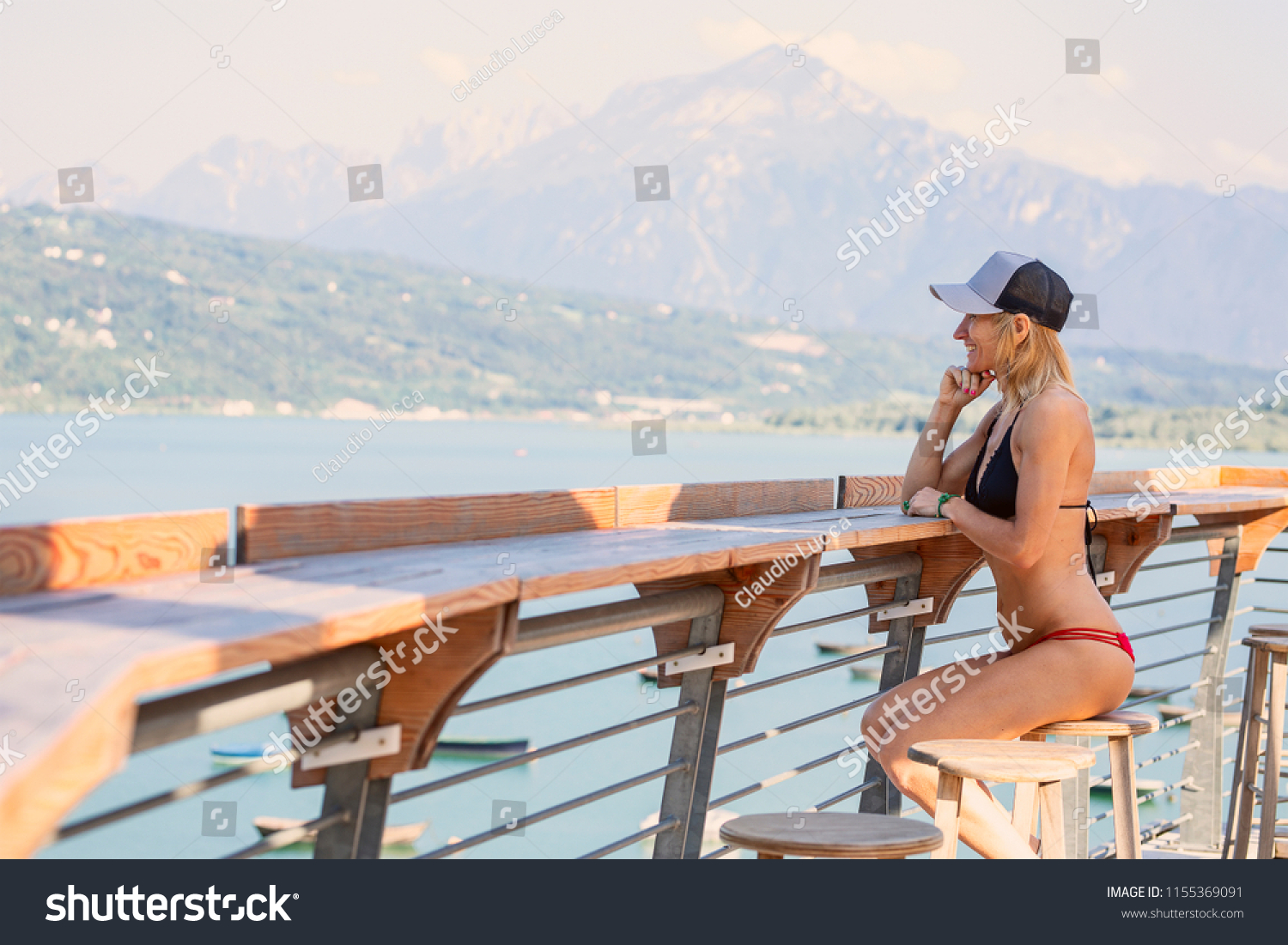 The beautiful young woman sits on a stool near the lake #1155369091