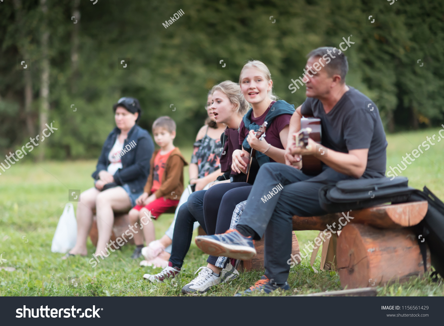 Zvenigorod, Russia, 15 AUG 2018. Group of happy friends with guitar in a central city park having fun outdoor. Camping couple. Adventure concept. Happy day. Musical concept. #1156561429