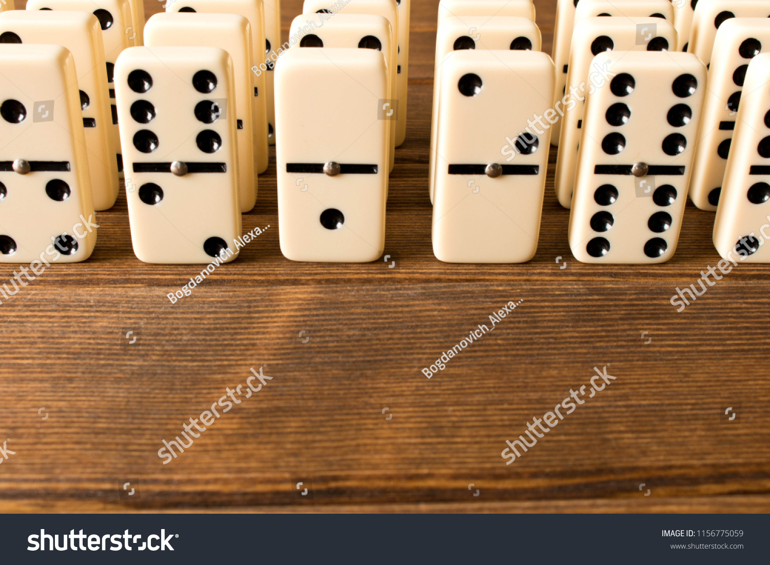 Playing dominoes on a wooden table. Close up. Dominoes game conc #1156775059