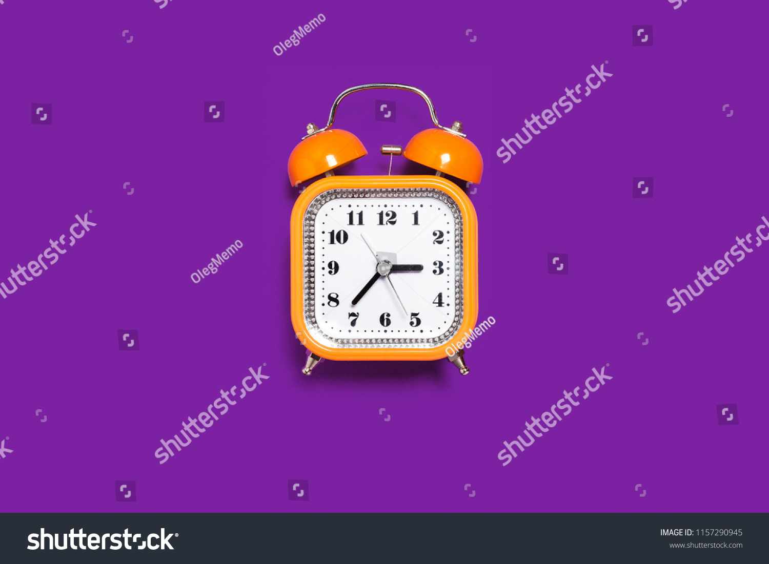 Vintage style orange metal alarm clock with bells standing on the purple surface isolated. back to school concept. free space for text #1157290945