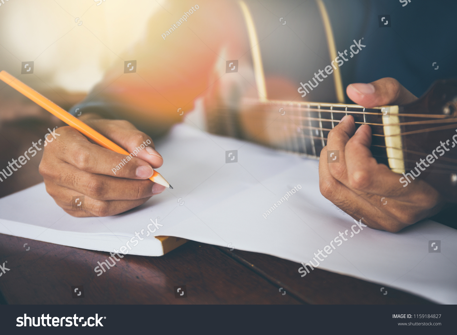 songwriter thinking and writing notes,lyrics in book at studio.man playing live acoustic guitar.concept for musician creative.artist composer in work process.people relaxing time with instrument #1159184827