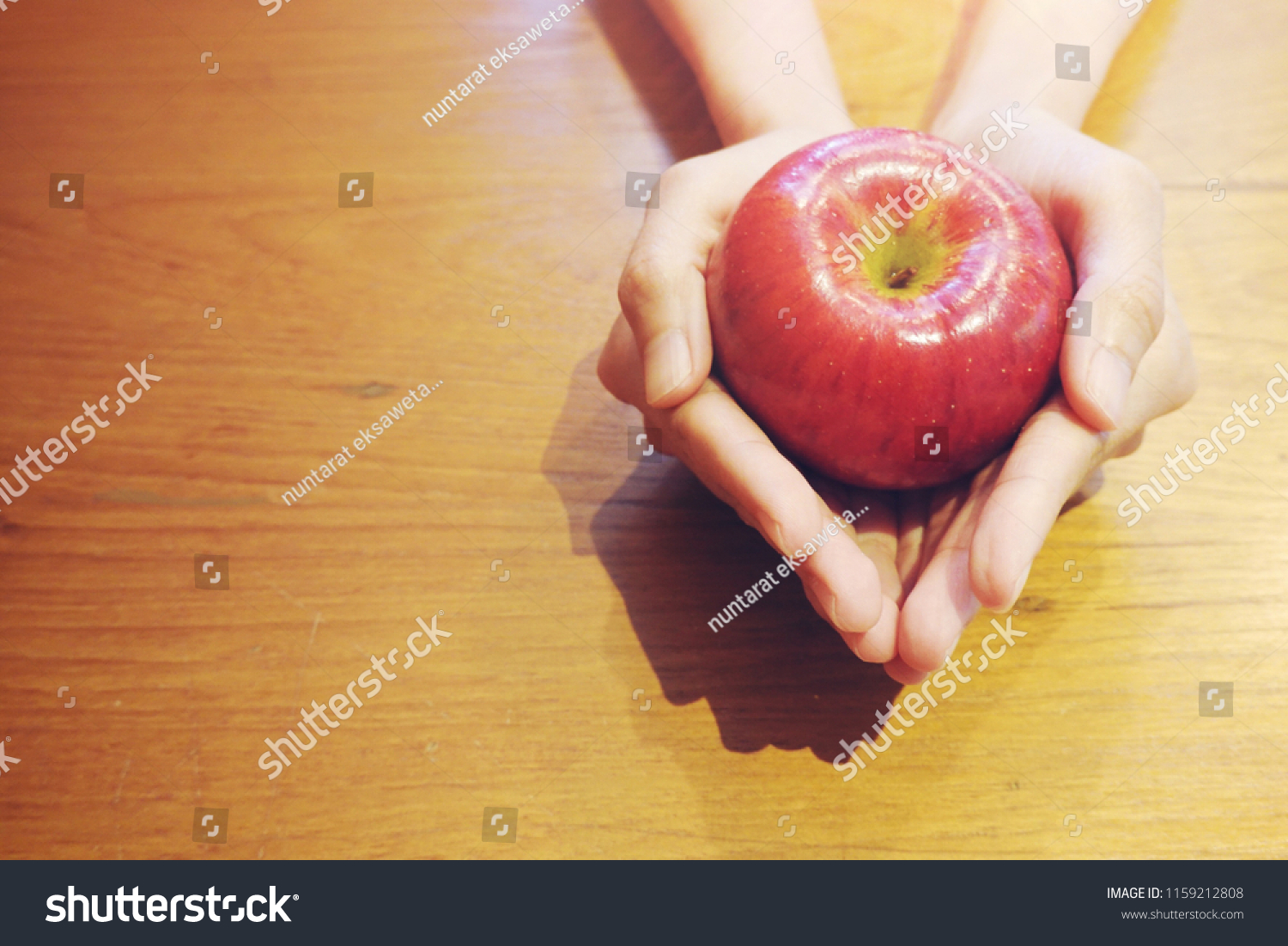 Hand holding red apple on wood table background, love yourself concept, healthy medical, you are what you eat concept,fruits, healthcare #1159212808