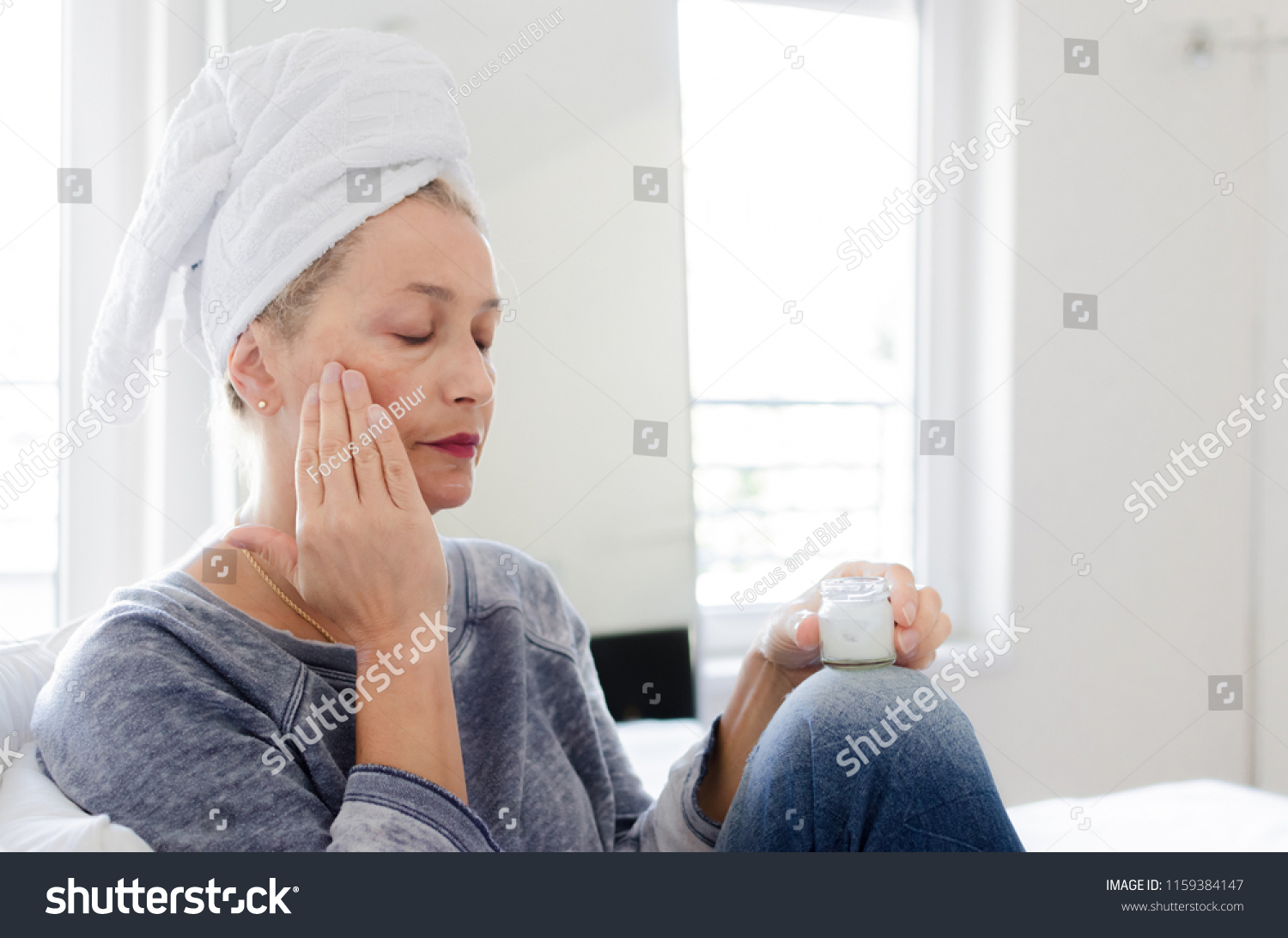 Portrait of beautiful senior woman putting on the cream. #1159384147