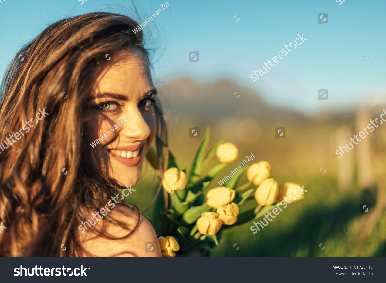 Beautiful brunette women in field with yellow tulip flowers #1161723418