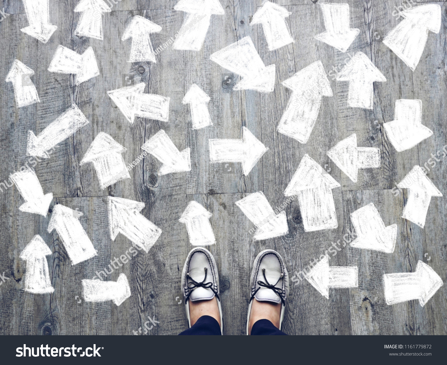 Top view of selfie feet on wooden floor background with white drawn many direction arrows , decision making , Choices concept, where to go, directions, business solutions #1161779872