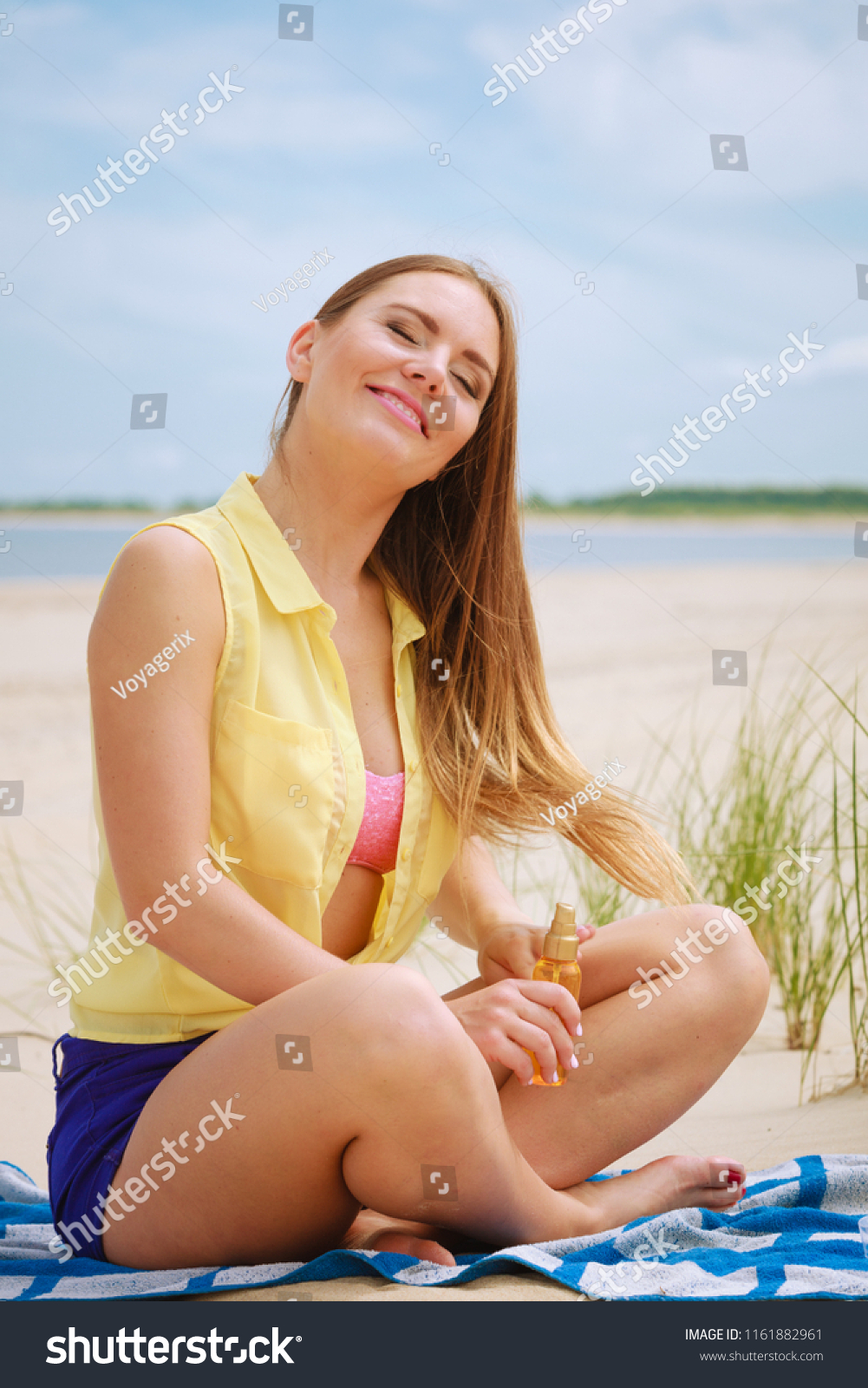 Skin protection in summer. Woman on beach using sun oil. Young beauty girl taking sunbath on sunny day. Holidays time. #1161882961