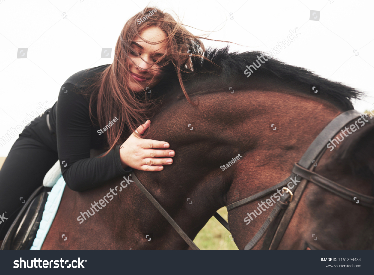Young cute girl hugging her horse while sitting astride. She likes animals. #1161894484