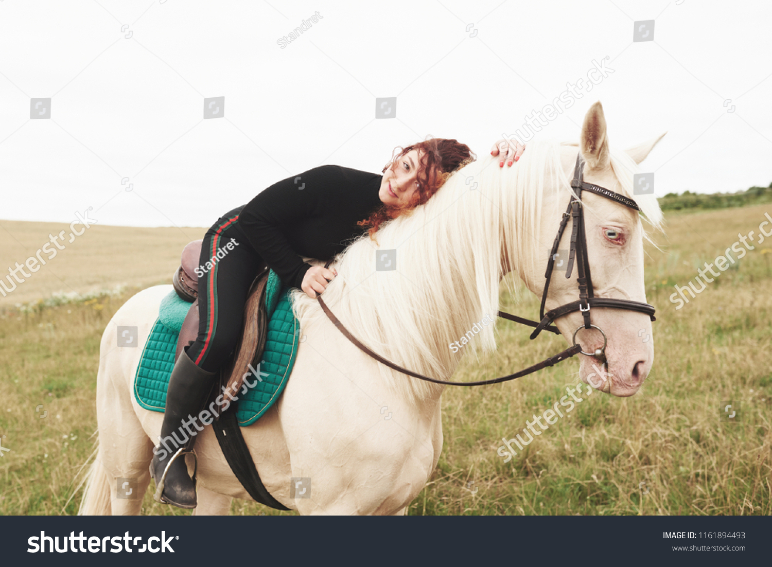 Young cute girl hugging her horse while sitting astride. She likes animals. #1161894493