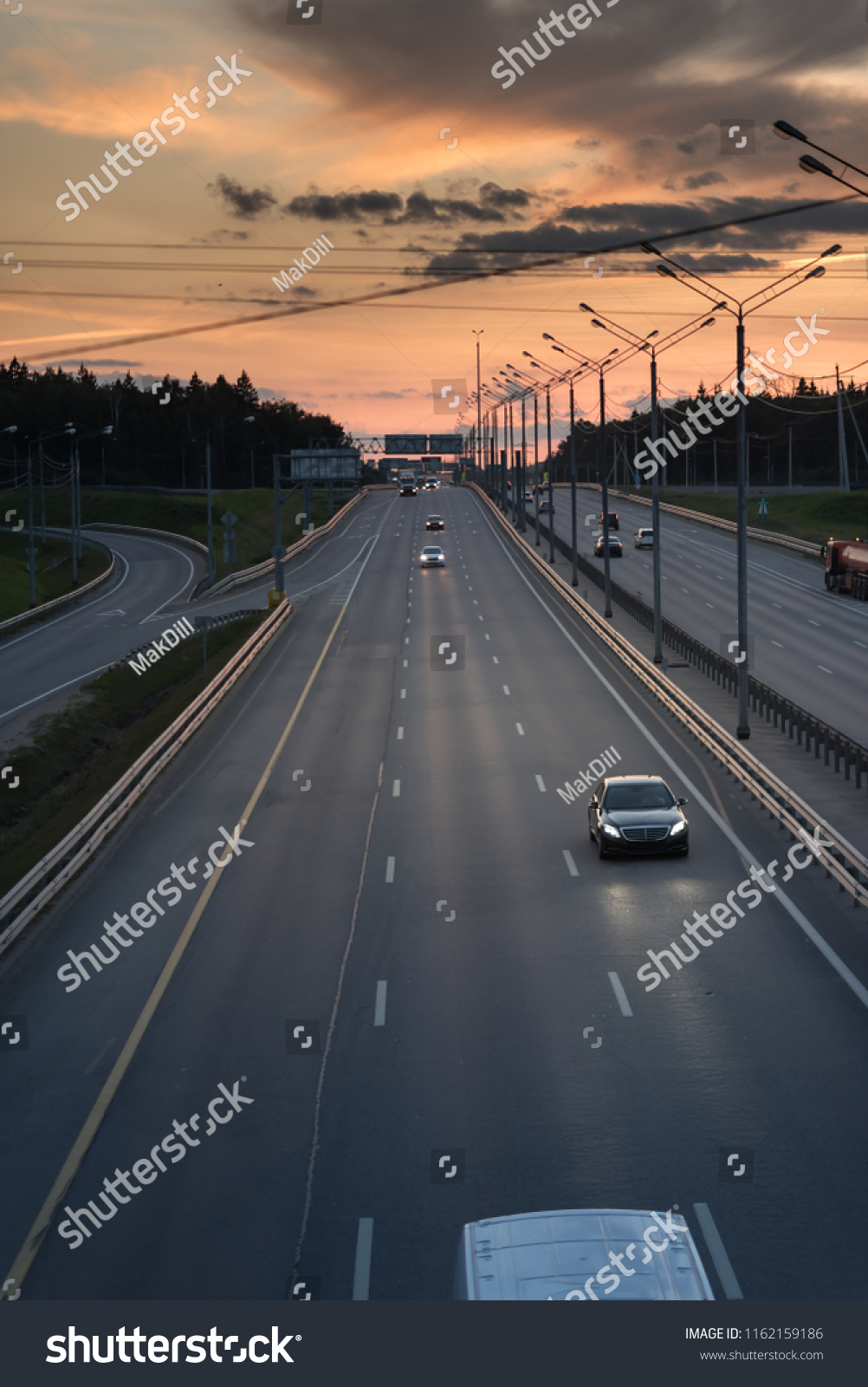 Highway traffic in sunset. minivan on the asphalt road with metal safety barrier or rail. Pine forest on the background #1162159186