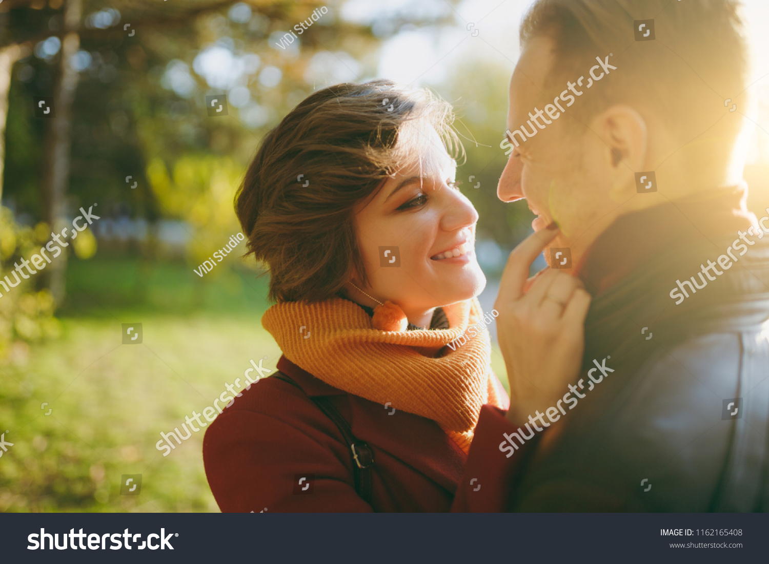 Close up of Young romantic couple smiling woman man in casual clothes embracing looking at each other on walk in autumn city park outdoors in sunny day. Love relationship family lifestyle concept #1162165408