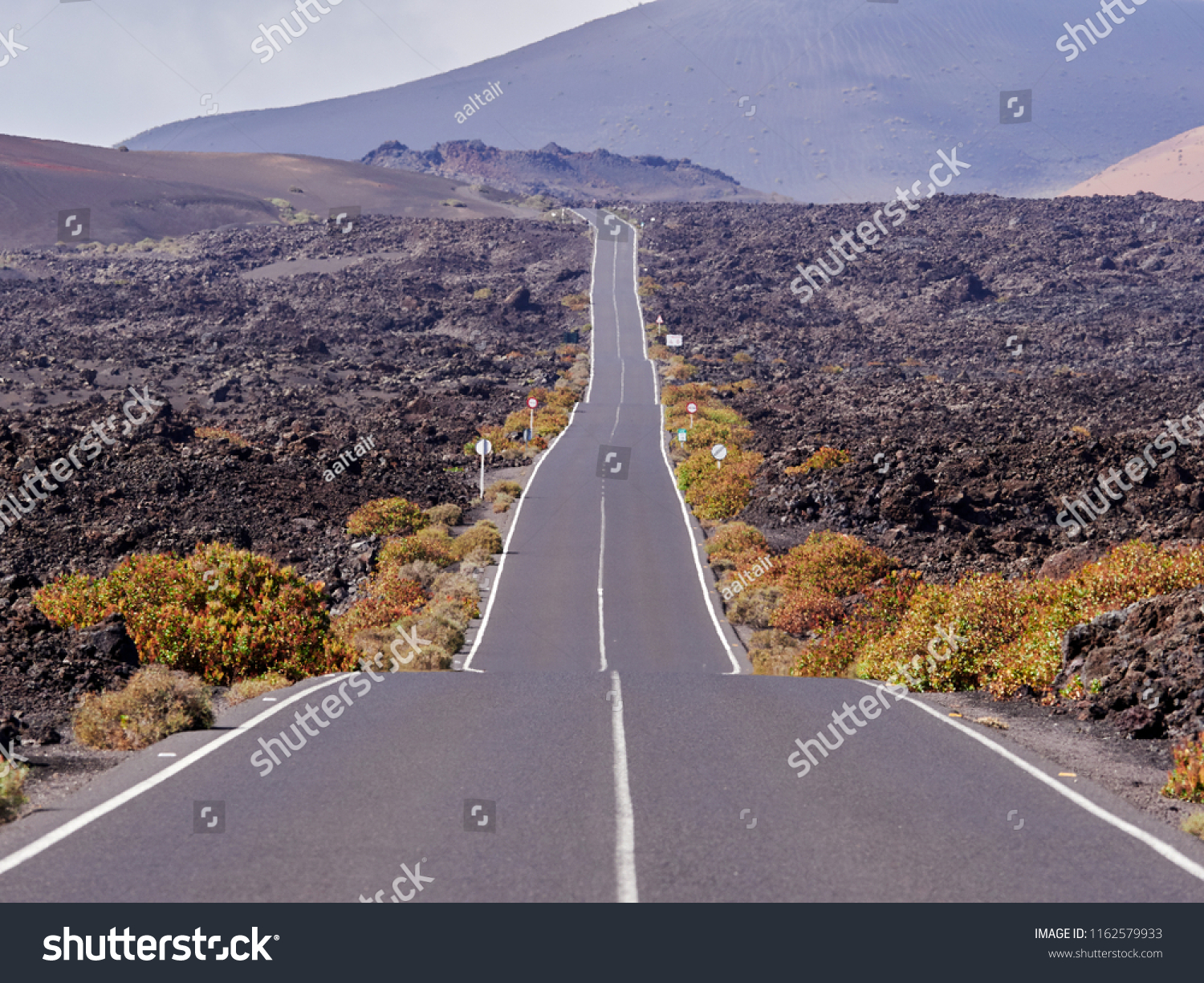 Empty endless highway through the volcanic landscape of Lanzarote island, Canary islands, Spain #1162579933