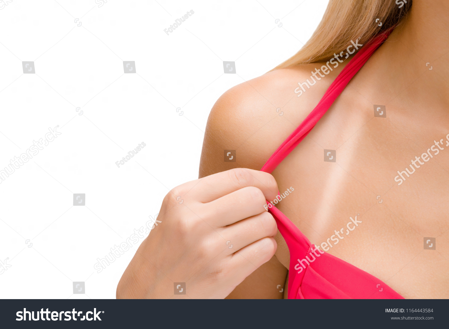 Young woman showing white stripe from swimsuit on shoulder zone after sunburn. Isolated on white background. Skin protection. Sunbathing concept. Front view. Empty place for text. #1164443584