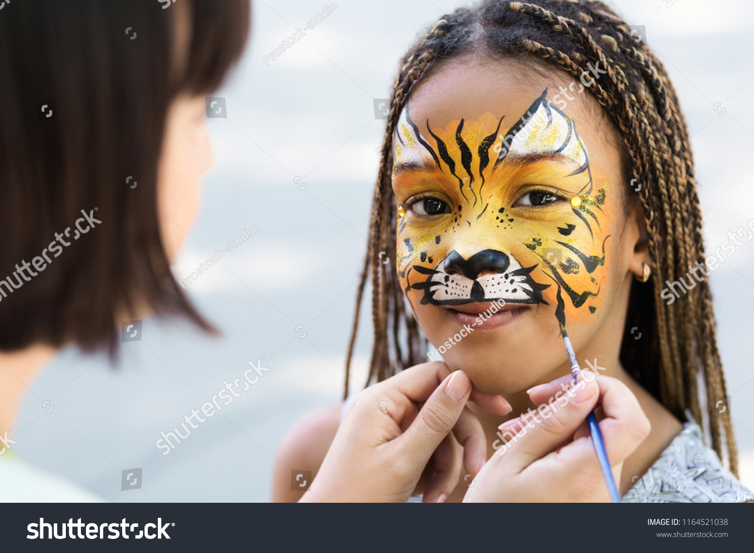 Cute little tiger. African-american girl getting face painting outdoors, having fun, copy space #1164521038
