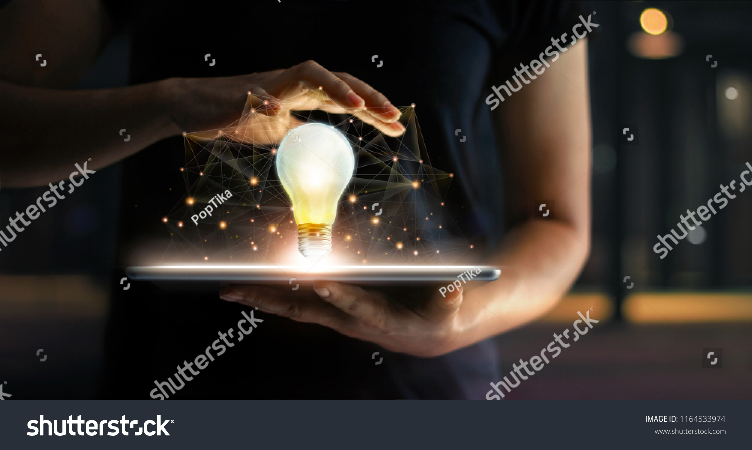 Innovation concept. Hands holding tablet and illuminated light bulb with global network connection on screen, Technology and communication on dark background. #1164533974