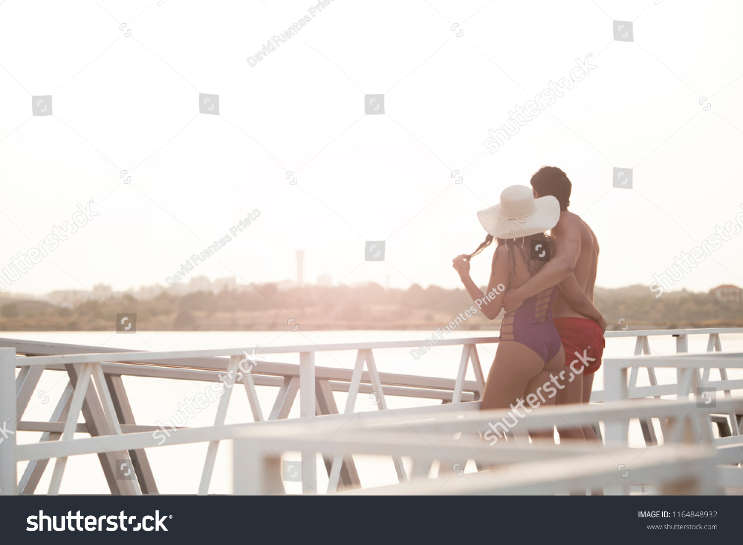 beautiful young couple embraced enjoying sunset on the hotel jetty #1164848932