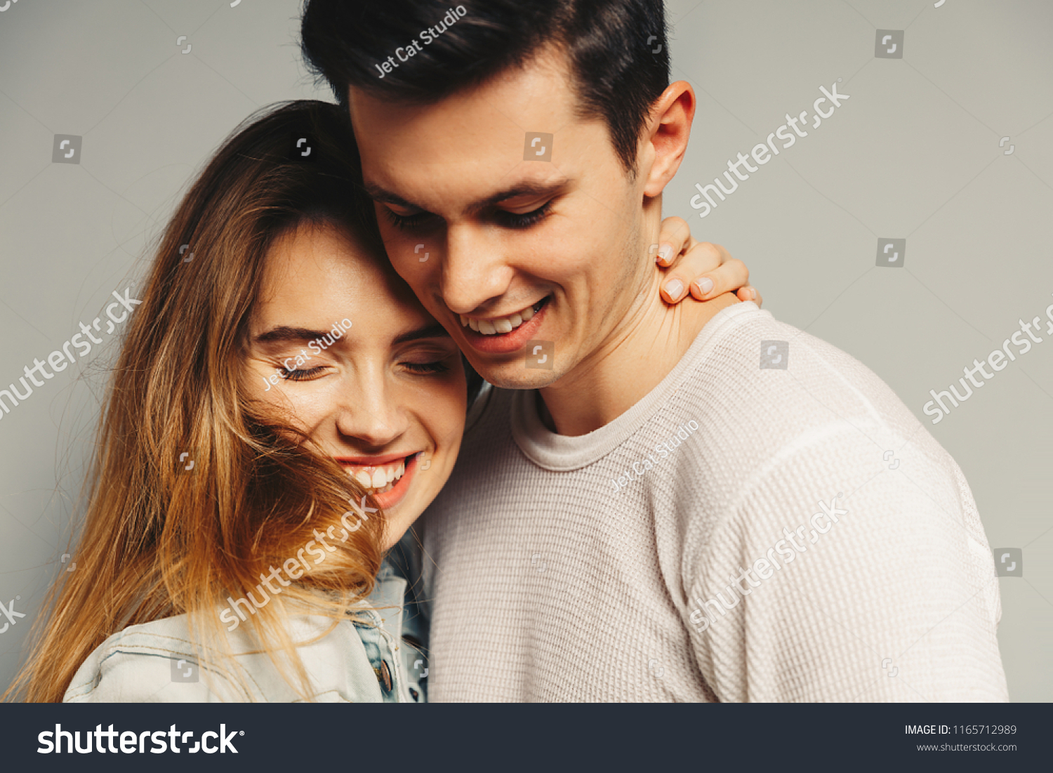 Portrait of beautiful young couple in casual clothes hugging and smiling, on gray background #1165712989