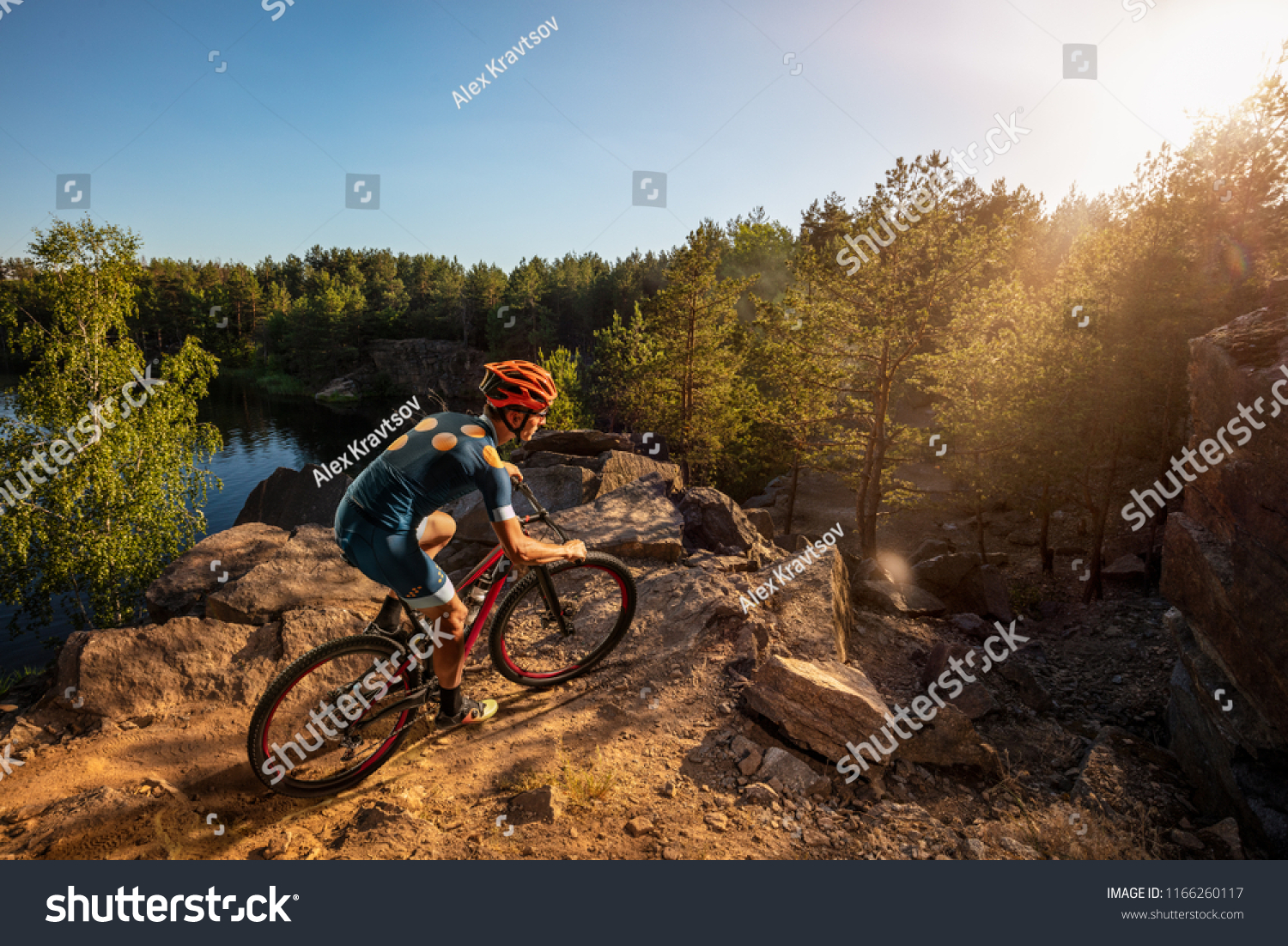 Cross-Country biker on stone trail near the lake. Male cyclist rides the rock #1166260117