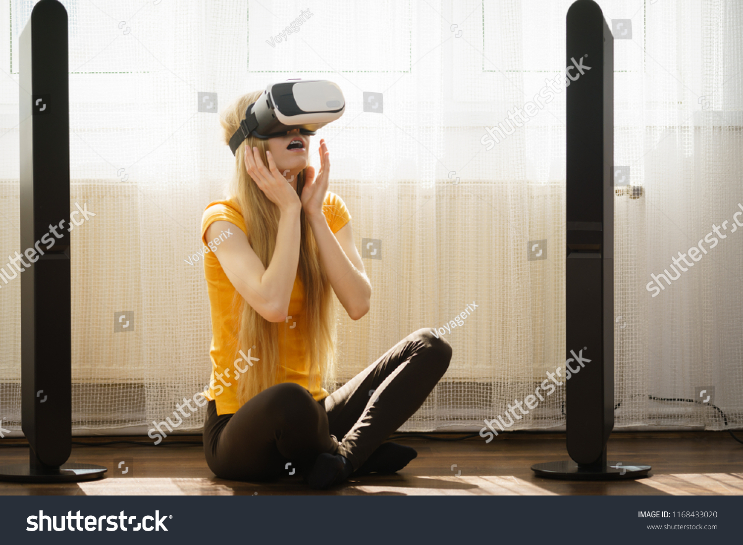 Young woman wearing virtual reality goggles vr 3d box sitting on floor in living room, listening to music. Connection, technology, new generation and progress concept. #1168433020